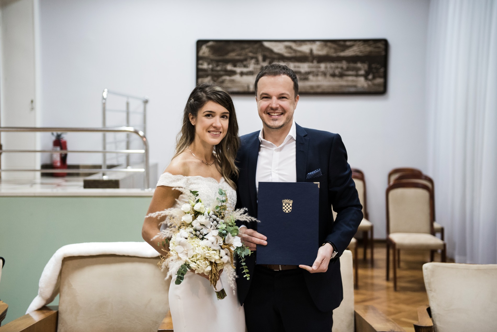 Proud bride and groom holding wedding certificate