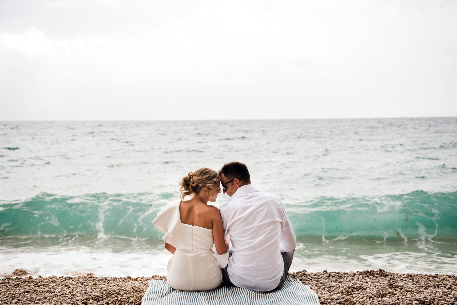 Married couple sitting at the ocean’s edge