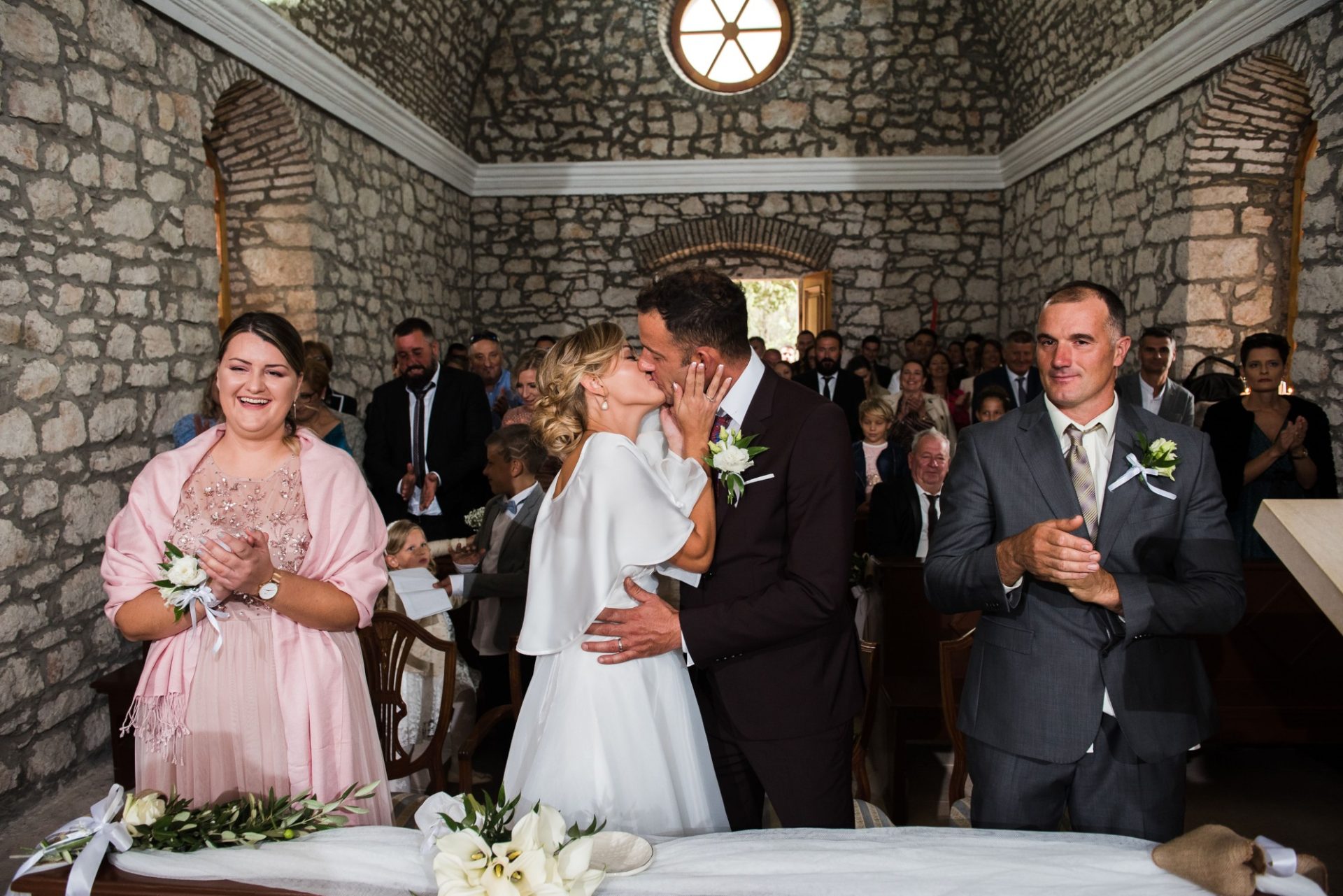 Kiss the bride moment in an old stone chapel