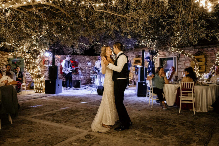 Married couple dancing outdoor under the lights and olive trees